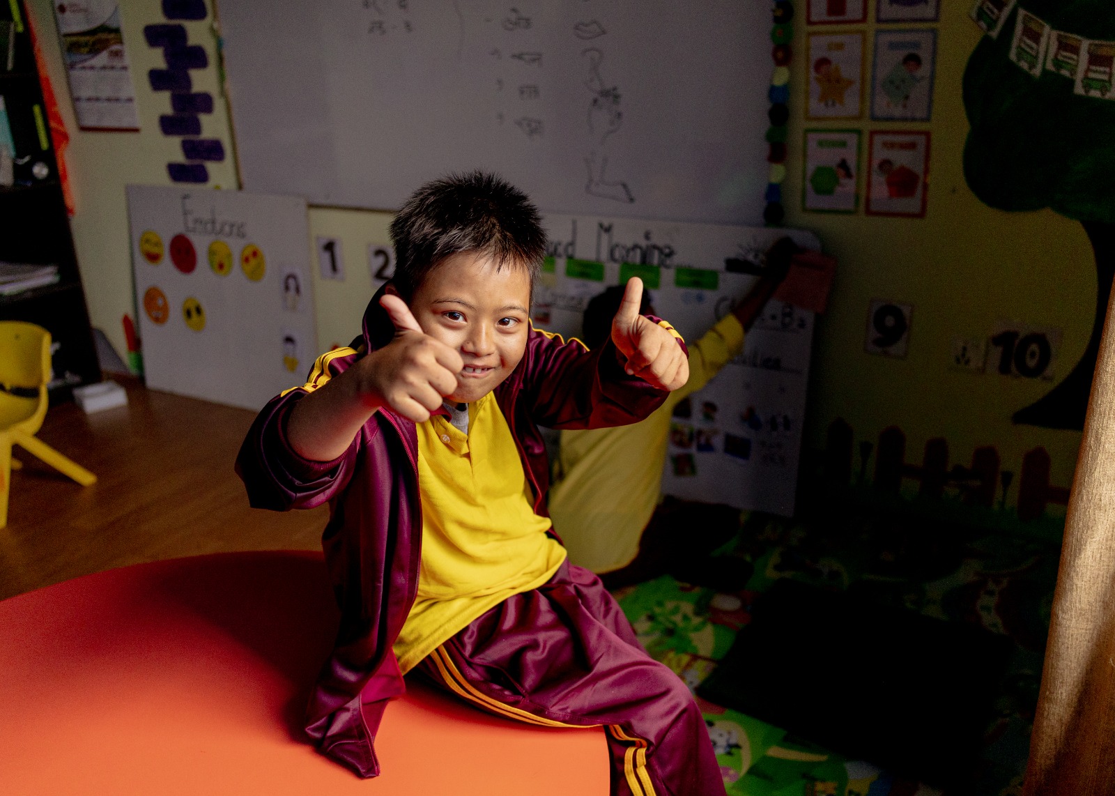 A student in uniform giving a thumbs up in a classroom
